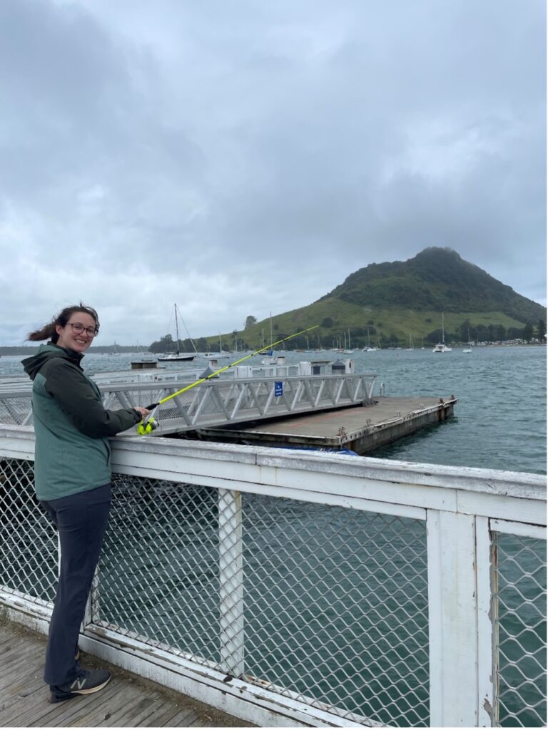 Chloé fishing for spottier from the wharf with Mount Maunganui in the background