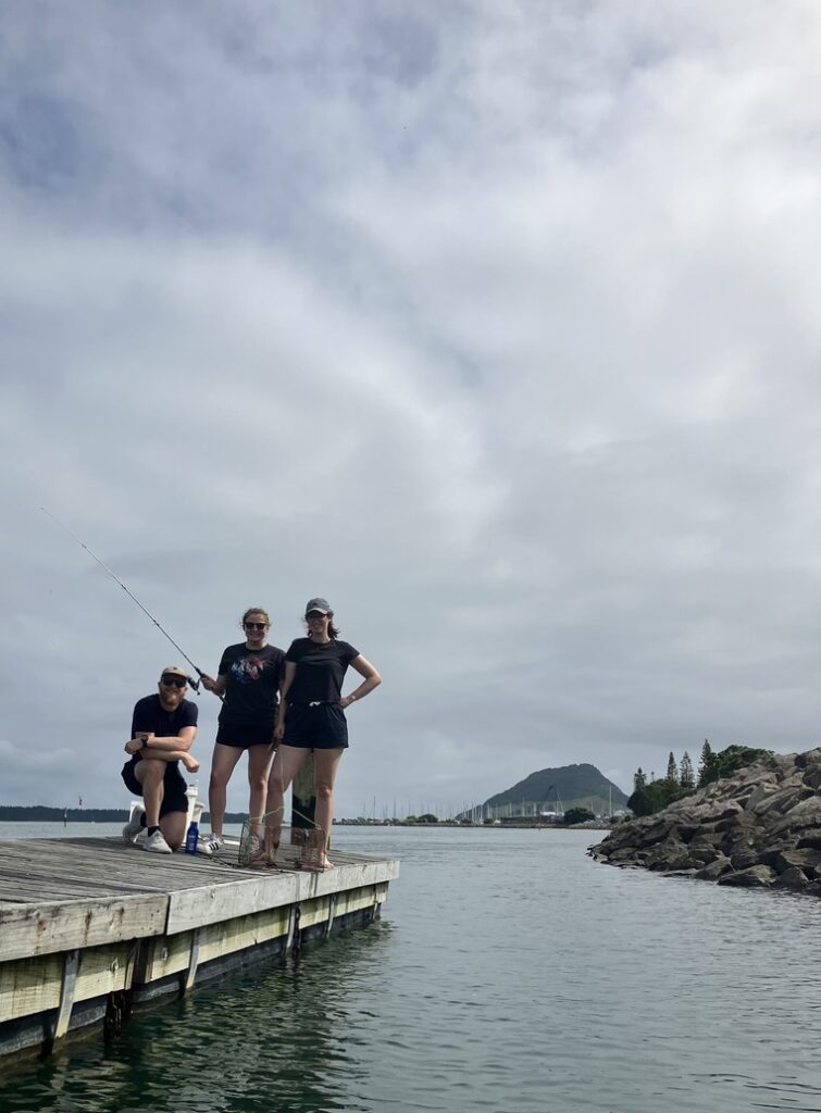 Kaj Kamstra (left), Haylee Quertermous (middle) and Chloé van der Burg (right) fishing for spotties in Tauranga, with Mount Maunganui as a backdrop.